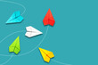 Red paper plane flying in a different direction than multicolored. Blue background. Copy space. The concept of innovative solutions, creativity. Business. Lifestyle.