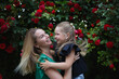 © Aleksandra Iarosh - mom hugs her little daughter against the background of a rose bush