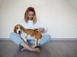 © Aleksandra Iarosh - a young woman combing a beagle dog with a furminator. grooming at home
