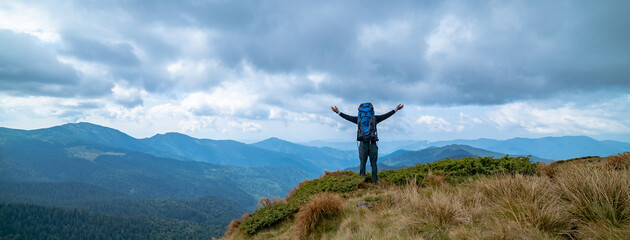 Wall Mural - the happy man standing on the mountain on the rainy clouds background