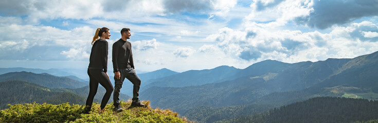 Wall Mural - the happy couple standing on the mountain with a picturesque cloudscape