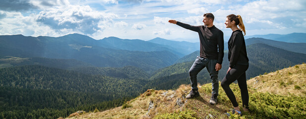 Wall Mural - the couple gesturing on the mountain with a picturesque cloudscape