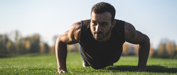 The handsome sportsman pushing up on the grass