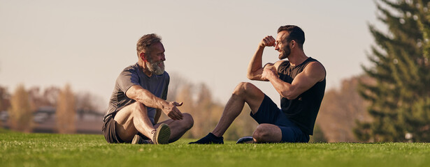 Wall Mural - The father and son sitting on the grass and talking