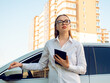 Modern woman businesswoman with a tablet in her hands near her car. 