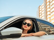 Modern beautiful woman businesswoman with glasses peeks out of her car.