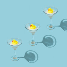 Creative Pattern Made With Yellow Rubber Duck And Bubble Bath Foam In Martini Cocktail Glass On Pastel Blue Background. Surreal Bathing Concept. Retro Style Aesthetic Idea.
