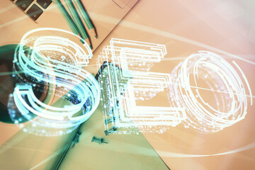 Double exposure of SEO drawing over study table background with computer. Concept of search. Top view.