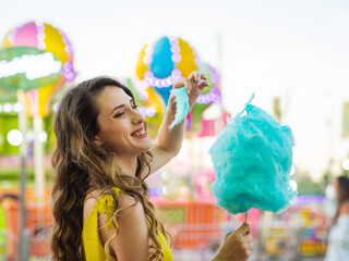 Wall Mural - Portrait of a Caucasian happy woman with blue candy floss on the carousel park in Spain