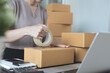 Young asian woman entrepreneur, online store owner packing products parcels, preparing to deliver to customer