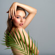 © Valua Vitaly - White woman with healthy skin of body and palm leaves. Tanned body of an attractive girl with green plants. Large palm leaves cover the body.