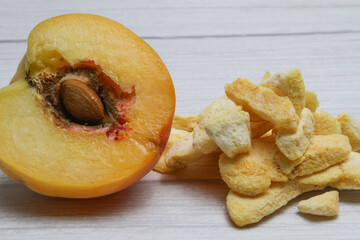 Fresh and freeze dried peach on the light wooden background.