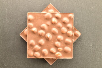 Two dark chocolate bars with nuts on a slate board, close-up, top view.