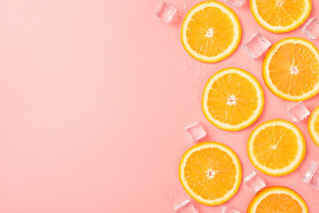 Wall Mural - Top view photo of orange slices ice cubes and water drops on isolated pastel pink background with blank space