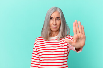 Wall Mural - middle age white hair woman looking serious showing open palm making stop gesture