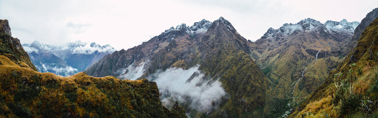 Wall Mural - Panoramic view of a valley on inca trail with the clouds between the mountains. On the way to Machu Picchu archaeological site from the Inca's ancient civilization in Peru. South America