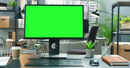 Wide green mock-up screen desktop computer standing on the desk in the modern creative office with bright creative loft for developers and designers where professional working at the background