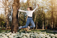 Enjoy Every Moment, Enjoying Life, Positive Emotions, Ways To Be Happier. Happy Young Woman Jumping And Enjoying Life At Green Park With Flowers.