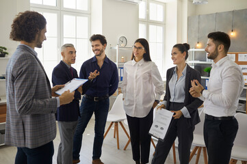 Various office workers stand and communicate with each other analyzing the data and making adjustments to the business plan. Senior man making suggestions to colleagues. Concept of teamwork.