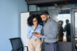 © insta_photos - Concentrated Indian male ceo businessman and female African American financial manager working on investment operations using tablet device standing in modern corporate office.