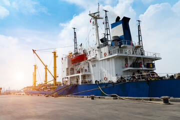 Cargo ships or break-bulk carrier.  Logistics and transportation of container  with working crane bridge in shipyard with sunlight at port, logistic import export and transport industry.