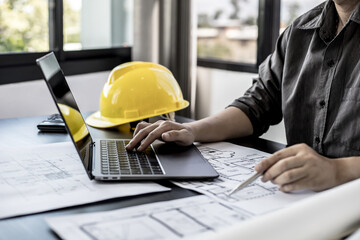 Architect engineers are using laptops to check house plans and print them out on paper after designing and presenting them to clients and requesting to modify some of the house plans. Interior Design.