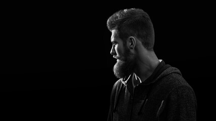 Wall Mural - Black and white shot of profile young handsome serious bearded man isolated on black background