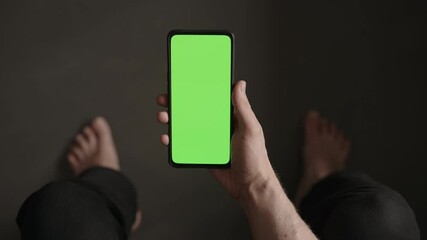 Poster - POV top view shot of man using phone with green screen indoor sitting on a couch