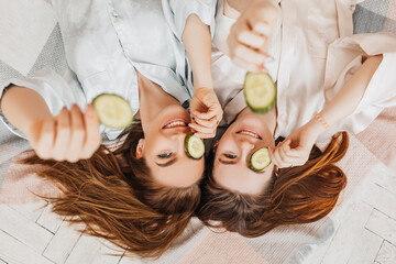 Wall Mural - two girls make homemade face and hair beauty masks. cucumbers for the freshness of the skin around t