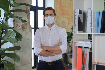 Sticker - Young businessman in medical mask standing in modern office.