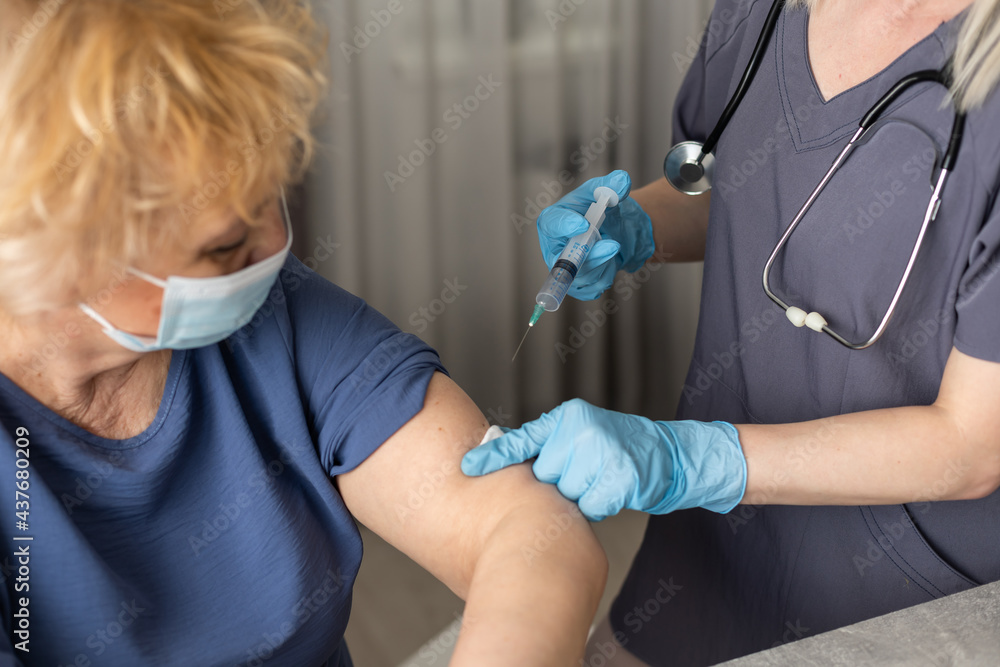 Senior woman receiving vaccine. Medical worker vaccinating an elderly patient against flu, influenza, pneumonia or coronavirus. - obrazy, fototapety, plakaty 