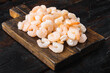 Boiled peeled shrimp prawns cooked, on wooden serving board, on old dark  wooden table