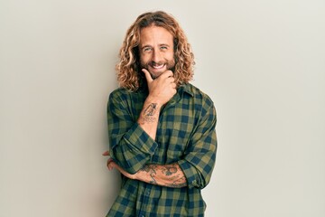 Wall Mural - Handsome man with beard and long hair wearing casual clothes looking confident at the camera smiling with crossed arms and hand raised on chin. thinking positive.