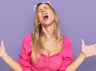 Canvas Print - Beautiful caucasian woman wearing sunglasses and summer style crazy and mad shouting and yelling with aggressive expression and arms raised. frustration concept.