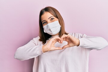 Sticker - Young beautiful woman wearing medical mask smiling in love doing heart symbol shape with hands. romantic concept.