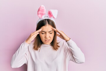 Canvas Print - Young beautiful woman wearing cute easter bunny ears with hand on head for pain in head because stress. suffering migraine.