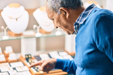 Wall Mural - senior grey-haired man smiling happy looking to showcase jewelry shop.