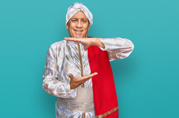 Sticker - Senior hispanic man wearing tradition sherwani saree clothes gesturing with hands showing big and large size sign, measure symbol. smiling looking at the camera. measuring concept.