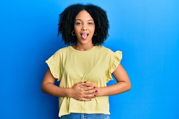 Wall Mural - Young african american girl wearing casual clothes sticking tongue out happy with funny expression. emotion concept.