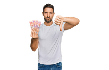 Sticker - Handsome man with beard holding south african 50 rand banknotes with angry face, negative sign showing dislike with thumbs down, rejection concept