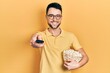 © Krakenimages.com - Young hispanic man eating popcorn using tv control smiling with a happy and cool smile on face. showing teeth.