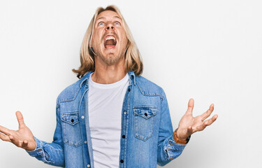 Poster - Caucasian man with blond long hair wearing casual denim jacket crazy and mad shouting and yelling with aggressive expression and arms raised. frustration concept.