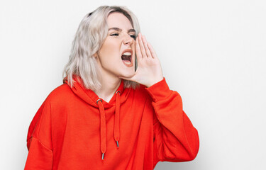 Poster - Young blonde girl wearing casual clothes shouting and screaming loud to side with hand on mouth. communication concept.