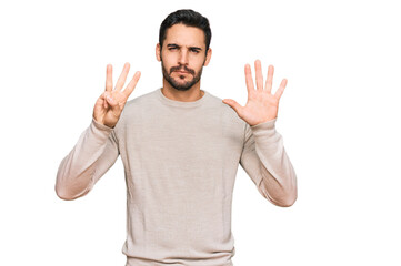 Young hispanic man wearing casual clothes showing and pointing up with fingers number eight while smiling confident and happy.