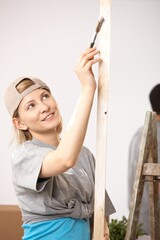 Canvas Print - Happy casual, caucasian couple busy renovating painting new home. Baseball cap, bucket, ladder.