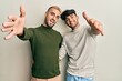 © Krakenimages.com - Homosexual gay couple standing together wearing casual clothes looking at the camera smiling with open arms for hug. cheerful expression embracing happiness.