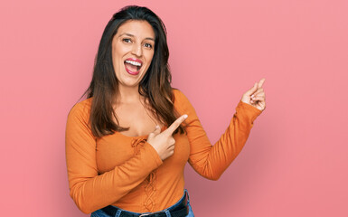 Beautiful hispanic woman wearing casual clothes smiling and looking at the camera pointing with two hands and fingers to the side.