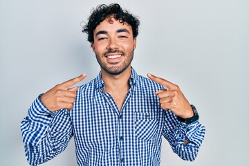 Sticker - Young hispanic man wearing casual clothes smiling cheerful showing and pointing with fingers teeth and mouth. dental health concept.