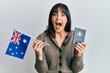 © Krakenimages.com - Young hispanic woman holding australian flag and passport celebrating crazy and amazed for success with open eyes screaming excited.