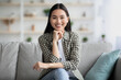 Potrait of happy asian woman sitting on sofa at home